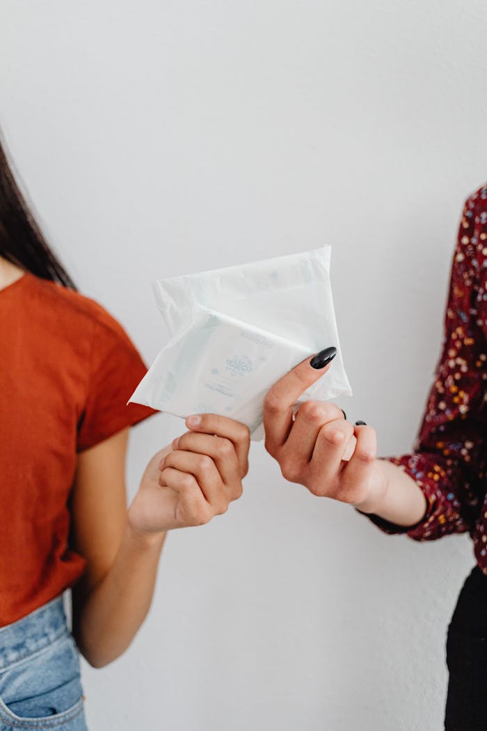 Close-up of two women holding a sanitary pad indoors.